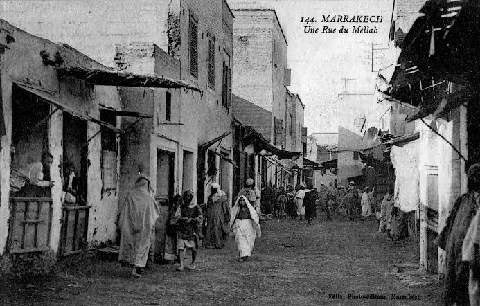 A rare early 20th-century postcard showing 'Une Rue du Mellah' in Marrakech — a street scene of the Marrakech Jewish quarter as it appeared at the height of its population, with residents in traditional dress going about their daily lives